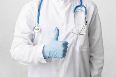 Doktor arka planda baş parmak hareketi gösteriyor