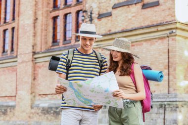Couple of tourists with map on city street clipart