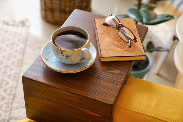 Cup of tea with book on armrest table in room