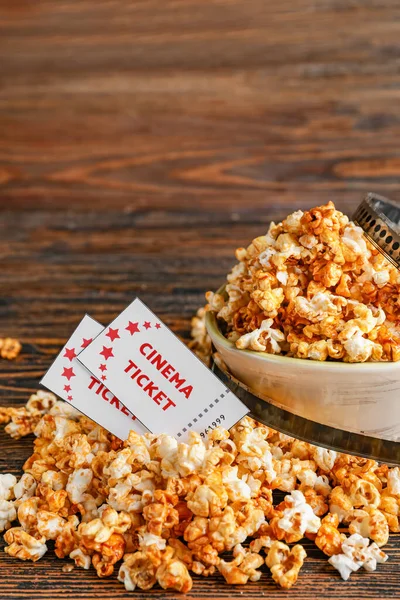 Bowl of tasty popcorn with cinema tickets on wooden background