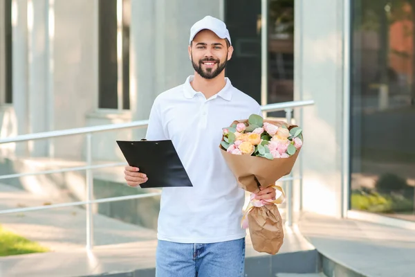 Delivery man with bouquet of beautiful flowers outdoors