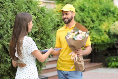 Dışarıdaki kuryeden çiçek alan genç bir kadın.