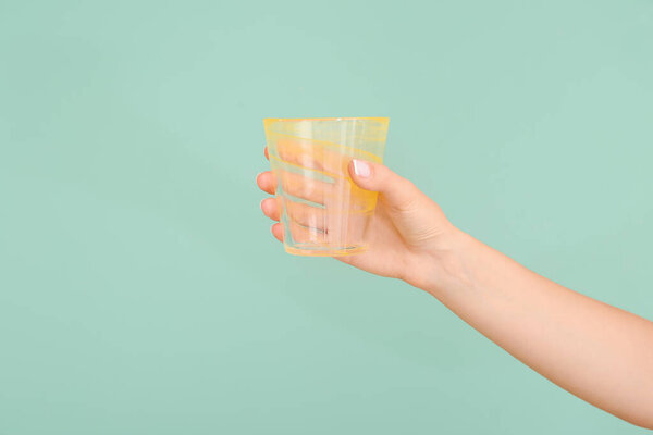 Hand with empty glass on color background