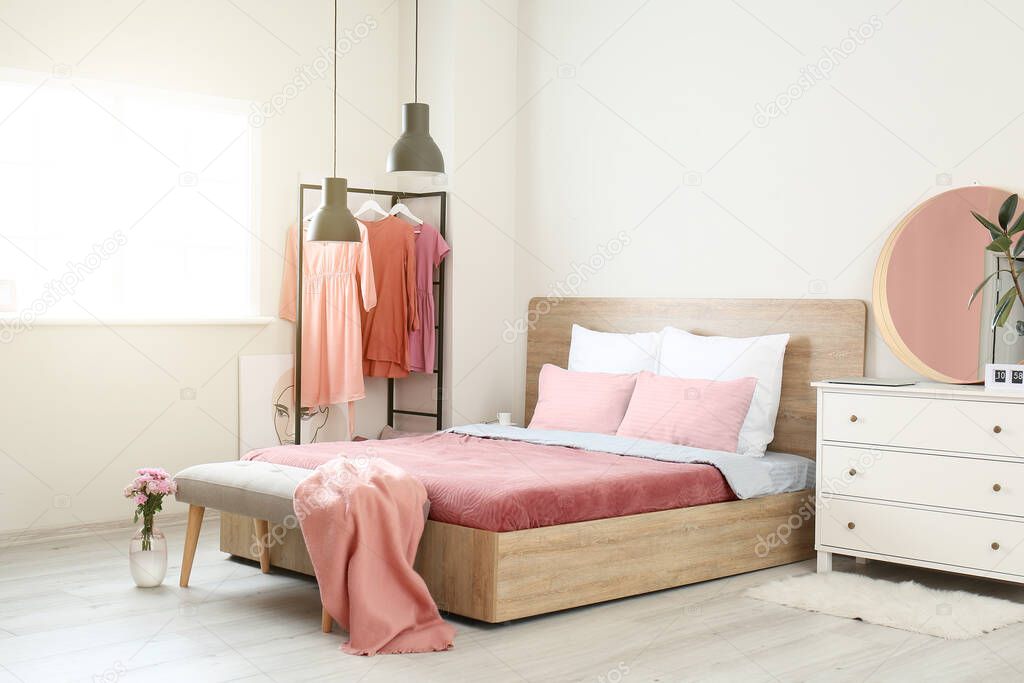 Stylish interior of room with big bed and bench