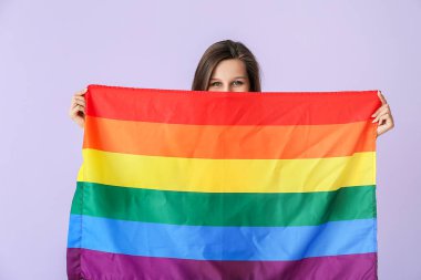 Renkli arka planda LGBT bayrağı olan genç bir kadın