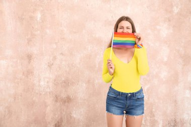 Renkli arka planda LGBT bayrağı olan genç bir kadın