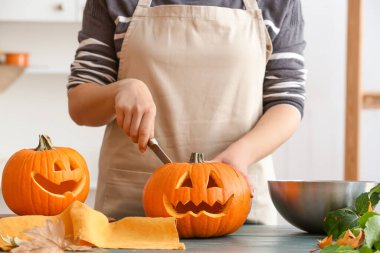 Masada Cadılar Bayramı için balkabağı oyan kadın.