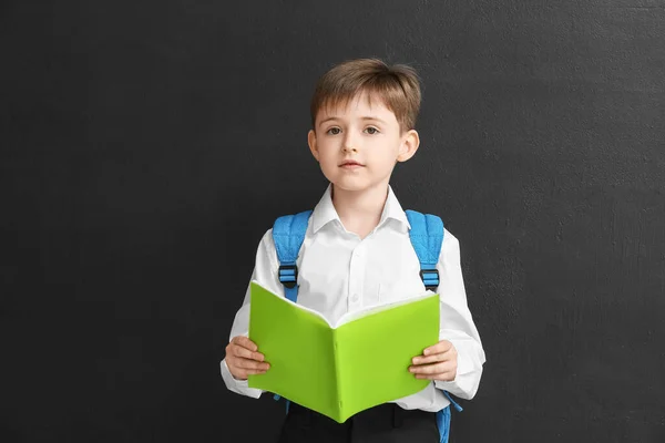 Kleiner Schuljunge Mit Lesebuch Auf Dunklem Hintergrund — Stockfoto