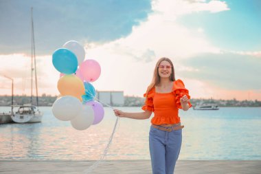 Nehir kenarında balonlu genç bir kadın.