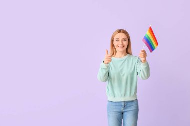 LGBT bayrağına sahip bir kadın renk arkaplanında başparmağını kaldırıyor