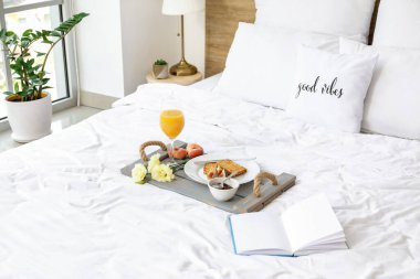 Lezzetli kahvaltı tepsisi ve yatağın üzerinde kitap