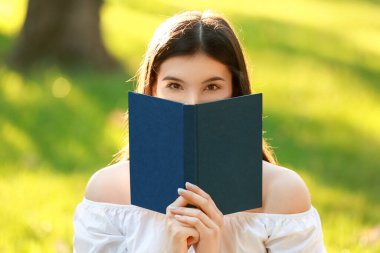 Parkta kitap okuyan güzel genç bir kadın.