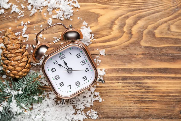 Alarm saati, kar, külahlar ve tahta arka planda köknar dalları