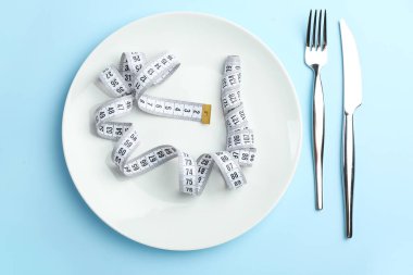 Renkli arka planda mezura ve çatal bıçak takımı olan bir plaka. İştahsızlık kavramı