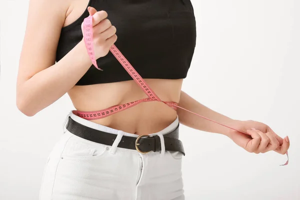 瘦小的女人以浅色背景测量她的腰围 厌食症的概念 — 图库照片