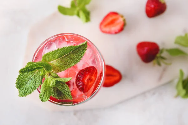 Hafif arkaplanda bir bardak taze çilekli mojito.