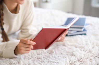 Evde kitap okuyan güzel genç bir kadın, yakın çekim.