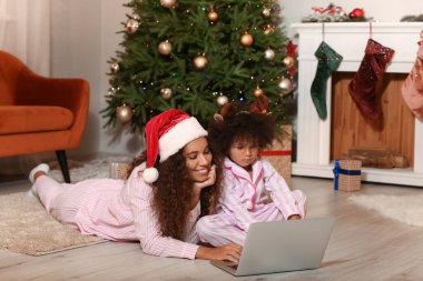Noel arifesinde evde dizüstü bilgisayarı olan tatlı Afro-Amerikalı kız ve annesi.