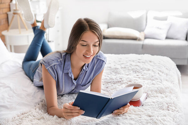 Beautiful young woman reading book at home