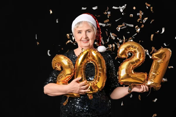 Elderly woman with figure 2021 on dark background. New Year celebration