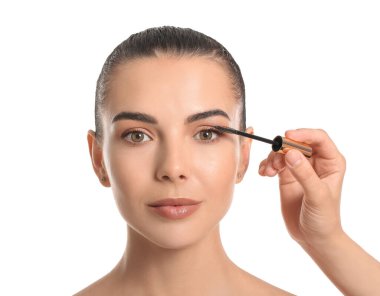 Makyaj sanatçısı beyaz arka planda güzel genç bir kadınla çalışıyor.