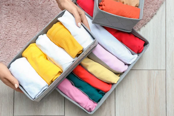 Woman with clean clothes in organizers at home