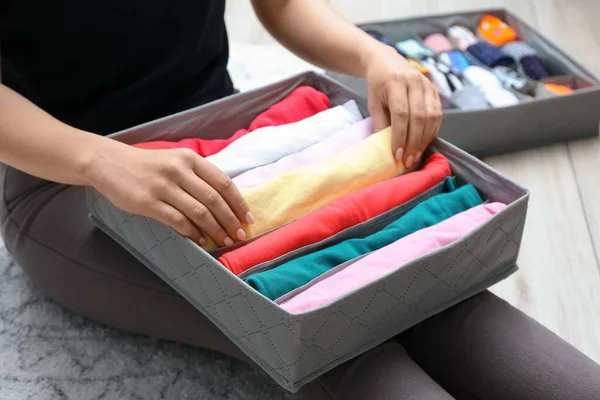 Woman with clean clothes in organizer at home, closeup