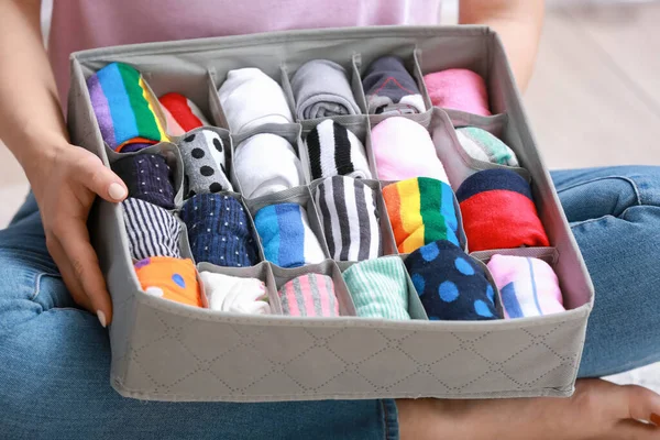 Woman with clean clothes in organizer at home, closeup