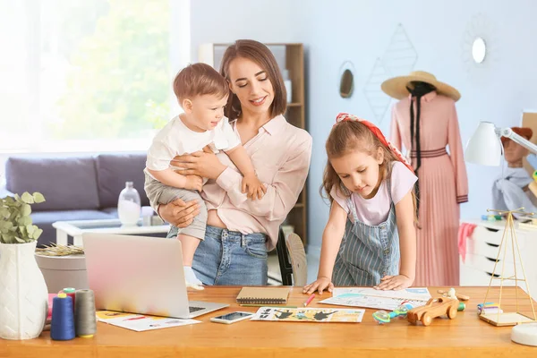 Working mother with little children in atelier