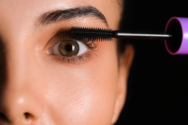 Bella Giovane Donna Che Applica Mascara Sullo Sfondo Scuro Primo — Foto Stock