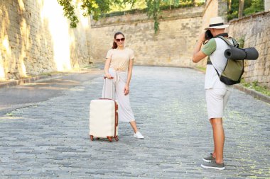 Erkek turist dışarıda karısının fotoğrafını çekiyor.