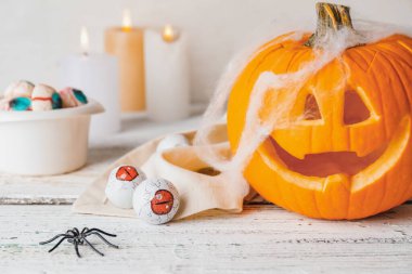 Beyaz ahşap arka planda balkabağı ve lezzetli şekerlerle Cadılar Bayramı kompozisyonu