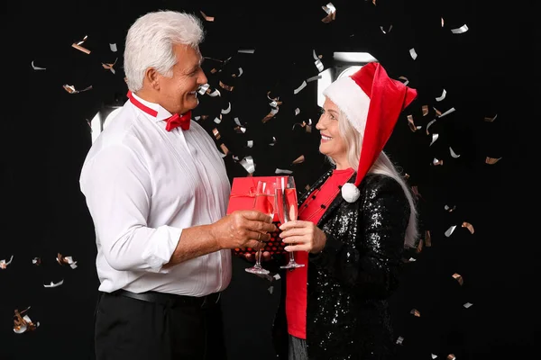 Пожилая Пара Шампанским Рождественским Подарком Тёмном Фоне — стоковое фото