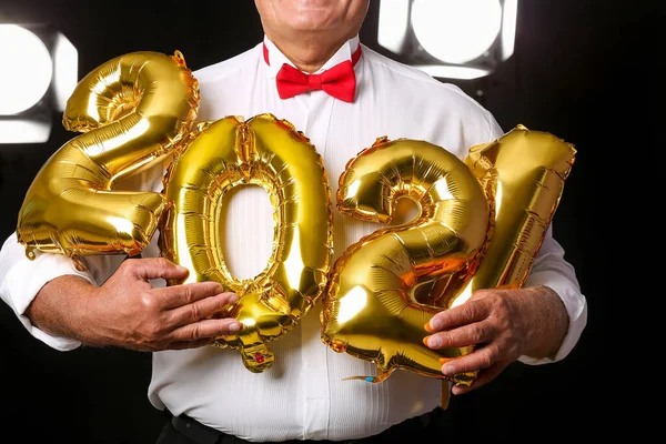 Elderly man with figure 2021 on dark background. New Year celebration