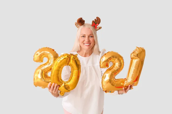 Elderly woman with figure 2021 on light background. New Year celebration