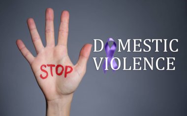 Gri arkaplanda DUR DOMESTIC VİYAZETİ yazan kadın eli