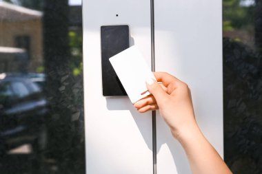 Woman using card to open door outdoors clipart