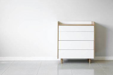 Çekmecelerin modern sandığı, odanın ışık duvarının yanında.