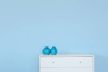 Odada renkli duvarın yanında vazolar olan modern çekmeceler.