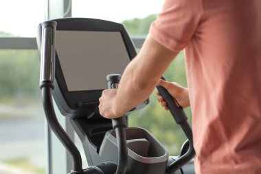 Spor salonunda egzersiz bisikleti eğitimi alan genç adam, yakın plan.