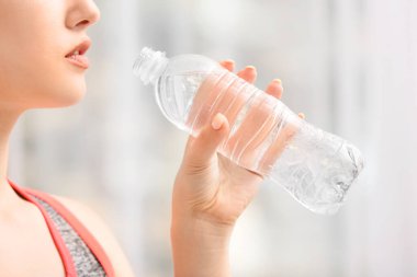 Evde bir şişe tatlı su taşıyan sporcu kadın.