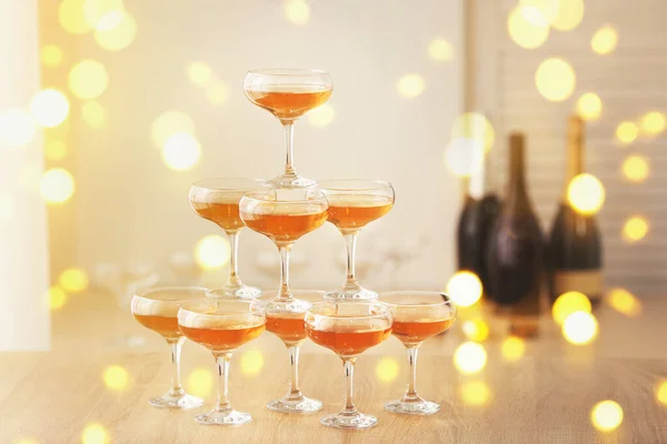 Tower made of glasses with champagne on table in room