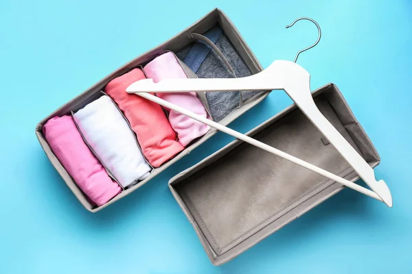 Organizers with clean clothes and hanger on color background