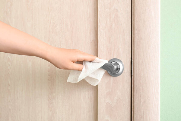 Woman disinfecting door handle, closeup