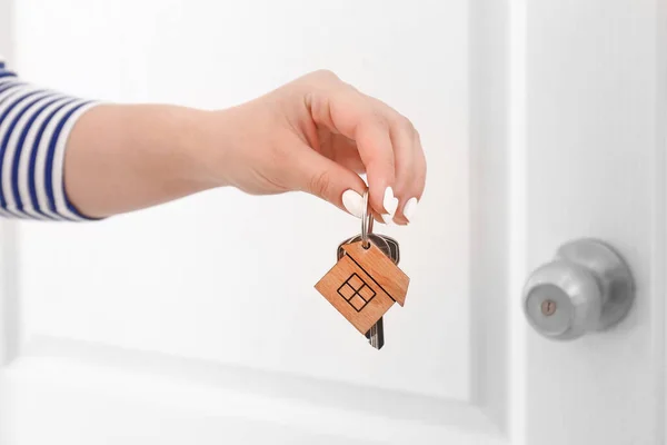 Woman with keys from house near door indoors