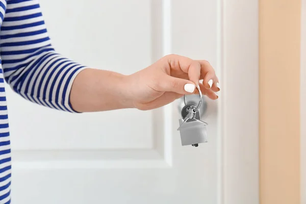 Woman with key from house near door indoors