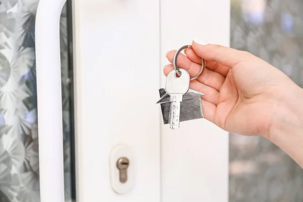 Woman with key from house near door outdoors