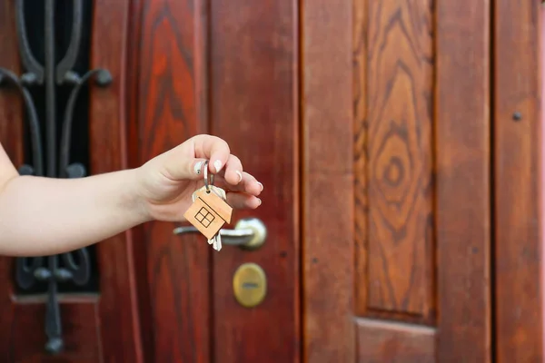 Woman with keys from house near door outdoors