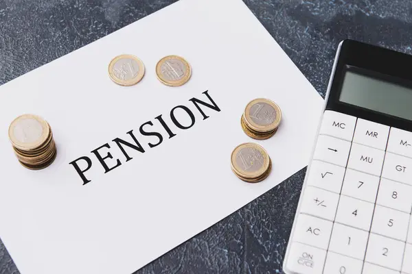 纸页上有单词Pension 硬币和深色背景的计算器 — 图库照片