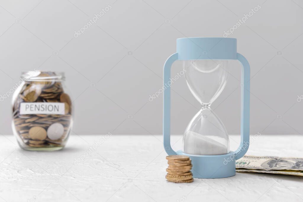 Hourglass with money on table. Concept of pension